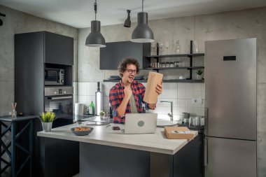 Beyaz bir adam online alışveriş ürünlerinin nakliye detaylarını kontrol etmek için akıllı telefon kullanıyor. Akıllı telefon uygulaması başvurusunu kontrol edin. Çevrimiçi detaylar mutlu bir gülümseme.