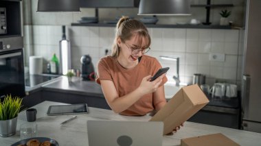 Beyaz bir kadın, online alışveriş ürünlerinin nakliye detaylarını kontrol etmek için akıllı telefon kullanıyor. Akıllı telefon uygulaması başvurusunu kontrol edin. Çevrimiçi detaylar mutlu bir gülümseme.