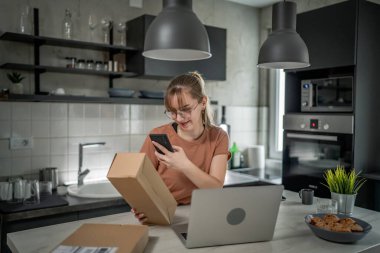 Beyaz bir kadın, online alışveriş ürünlerinin nakliye detaylarını kontrol etmek için akıllı telefon kullanıyor. Akıllı telefon uygulaması başvurusunu kontrol edin. Çevrimiçi detaylar mutlu bir gülümseme.