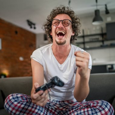 Yetişkin erkek, beyaz erkek, evde oyun konsolu video oyunu oynuyor. Oyun kumandası sizde. Keyfinize bakın ve kazanın ve başarı konseptini kopyalayın.