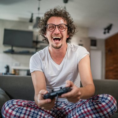 Yetişkin erkek, beyaz erkek, evde oyun konsolu video oyunu oynuyor. Oyun kumandası sizde. Keyfinize bakın ve kazanın ve başarı konseptini kopyalayın.