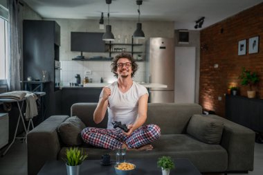 Yetişkin erkek, beyaz erkek, evde oyun konsolu video oyunu oynuyor. Oyun kumandası sizde. Keyfinize bakın ve kazanın ve başarı konseptini kopyalayın.