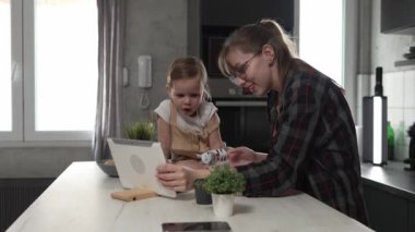 Küçük beyaz kız çocuğu ve annesi ya da teyzesi evde dijital tabletin önünde parmak kuklalarıyla oynuyorlar. Keyif verici bağlanma konsepti yavaş çekimde. 