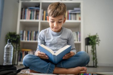 Beyaz tenli öğrenci evde ders kitabı okuyor. Okula hazırlanmayı öğrenin.