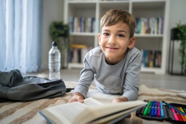 Beyaz tenli öğrenci evde ders kitabı okuyor. Okula hazırlanmayı öğrenin.