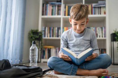 Beyaz tenli öğrenci evde ders kitabı okuyor. Okula hazırlanmayı öğrenin.