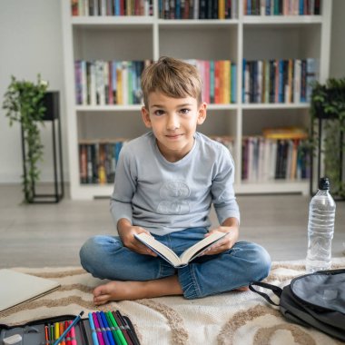 Beyaz tenli öğrenci evde ders kitabı okuyor. Okula hazırlanmayı öğrenin.