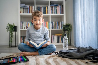 Beyaz tenli öğrenci evde ders kitabı okuyor. Okula hazırlanmayı öğrenin.