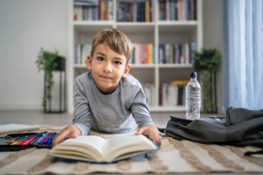 Beyaz tenli öğrenci evde ders kitabı okuyor. Okula hazırlanmayı öğrenin.