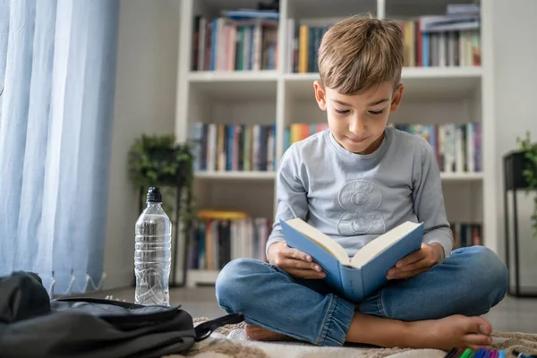 Beyaz tenli öğrenci evde ders kitabı okuyor. Okula hazırlanmayı öğrenin.