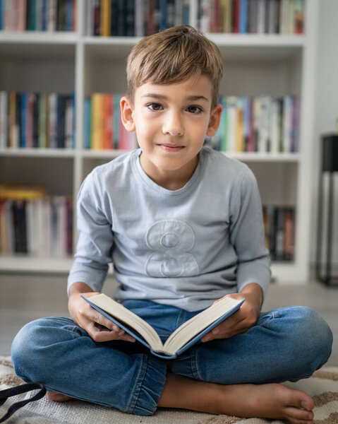 caucasian boy pupil student read book at home on the floor study learn prepare for school
