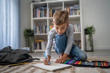 Bir okul çocuğu. Küçük beyaz bir çocuk evde oynuyor. Ev ödevlerini yapıyor. Çocukluk gelişimi ve eğitim kavramı.