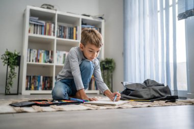 Bir okul çocuğu. Küçük beyaz bir çocuk evde oynuyor. Ev ödevlerini yapıyor. Çocukluk gelişimi ve eğitim kavramı.