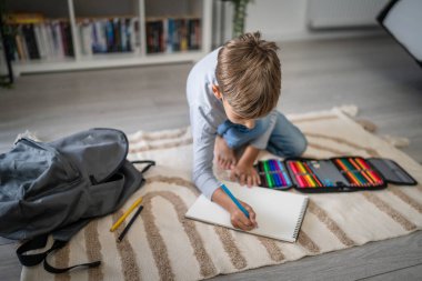 Bir okul çocuğu. Küçük beyaz bir çocuk evde oynuyor. Ev ödevlerini yapıyor. Çocukluk gelişimi ve eğitim kavramı.