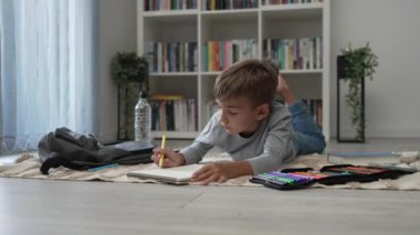 Bir okul çocuğu. Küçük beyaz çocuk evde oynuyor. Evde çizim yapıyor. Çocukluğunda ödev geliştiriyor.