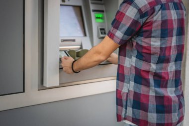 Genç bir erkek öğrenci kredi kartı kullanıyor ve ATM 'den para çekiyor.