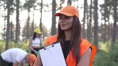 Gönüllü arkadaş portresi yaz günü yavaş çekimde çöpleri ve temiz orman doğasını toplamaya hazırlanıyor.