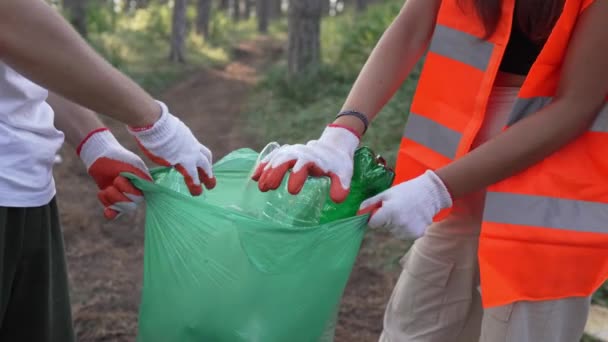 ティーンエイジャーの友人のグループ 男性と女性の慎重な男性 ゴミ捨てプラスチックボトルと森から紙を拾う女性 晴れた日の環境ケアのエコロジーの概念で自然をきれいにする — ストック動画