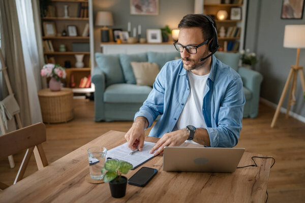 Один человек кавказский фрилансер работает из дома с наушниками на голове на ноутбуке диспетчер поддержки клиентов