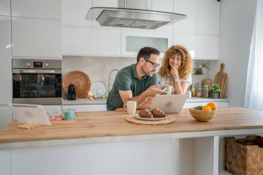 Mutlu çift Kafkasyalı yetişkin erkek ve kadın karı ve koca sabah rutini kahvaltıda evde fotokopi odasında dizüstü bilgisayar kullanın.