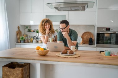 Mutlu çift Kafkasyalı yetişkin erkek ve kadın karı ve koca sabah rutini kahvaltıda evde fotokopi odasında dizüstü bilgisayar kullanın.