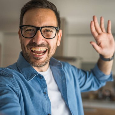 Bir yetişkin portresi, sakallı ve gözlüklü beyaz bir erkeğin mutlu bir gülümseme ile kendi portresinin fotokopisini çeker.