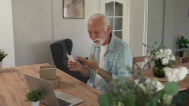 Bir son sınıf büyükbaba emeklisi gri saçlı ve sakallı hediye alıyor açık kutuda kart okuyarak mutlu bir gülümseme evde dizüstü bilgisayarın önünde internetten fotokopi odası arıyor.