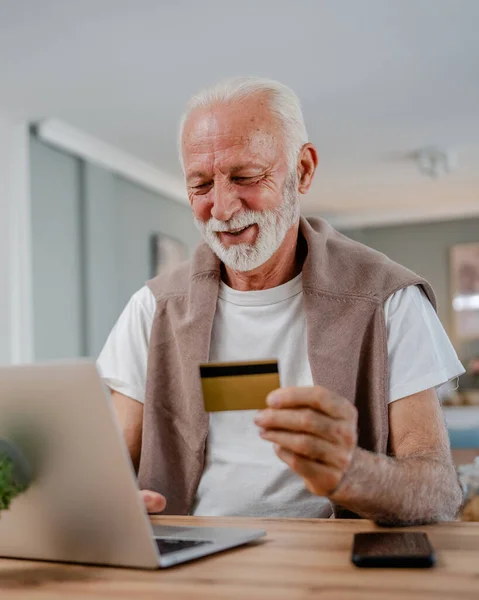 Stock image One man senior caucasian male grandfather sit at home use credit card and laptop computer shopping online use internet for online purchase active modern senior