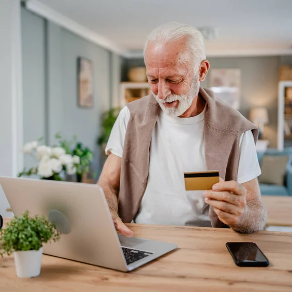 stock image One man senior caucasian male grandfather sit at home use credit card and laptop computer shopping online use internet for online purchase active modern senior