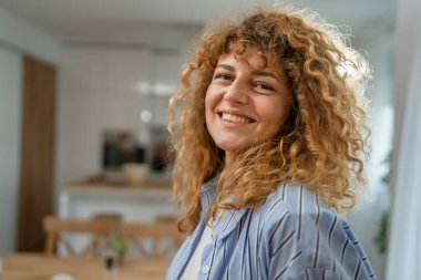 Yetişkin beyaz bir kadının portresi. Mutlu, kıvırcık saçlı.