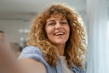 Yetişkin beyaz bir kadının portresi. Mutlu, kıvırcık saçlı.