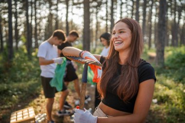 Beyaz kadın eylemci portresi. Ormandan atık plastik şişe kağıdı toplarken güneşli bir günde çevre koruma kampanyası konseptinde doğayı temizlerken.