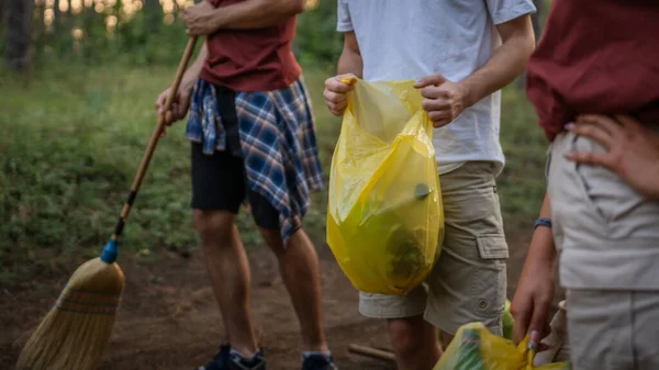 未知の慎重な人の手は 日当たりの良い環境ケアエコロジーの概念で自然をきれいにする森からゴミのプラスチックボトルと紙を拾う袋を保持しています — ストック写真