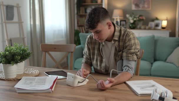 テーブルデスクに座っている10代の若い男性の1人のティーンエイジャーは 家庭での血圧を測定します 実際の人の医療コンセプト — ストック動画