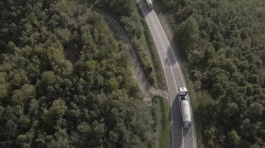 Sırbistan 'da yeşil ve manzara taşımacılığı ve seyahat konseptiyle çevrili dolambaçlı yol boyunca giden bahar aracı kamyonları sırasında bir dağ sırasındaki eğri asfalt bir yolun hava aracı görüntüleri