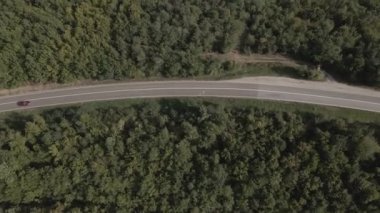 Sırbistan 'da yeşil ve manzara taşımacılığı ve seyahat konseptiyle çevrili dolambaçlı yol boyunca giden bahar aracı otomobili sırasında, bir dağ sırasındaki eğimli asfalt bir yolun hava aracı görüntüleri