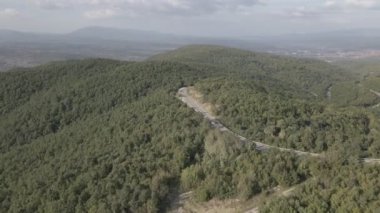 Sırbistan 'da yeşil ve manzara taşımacılığı ve seyahat konseptiyle çevrili dolambaçlı yol boyunca giden bahar aracı otomobili sırasında, bir dağ sırasındaki eğimli asfalt bir yolun hava aracı görüntüleri