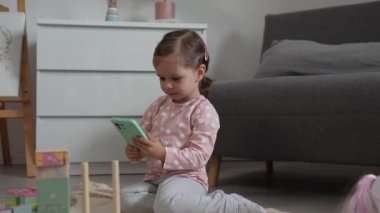 Bir kız çocuğu cep telefonuyla video oyunu oynuyor.