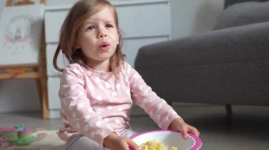 Kafkasyalı bir çocuk evde elleriyle makarna yiyor.