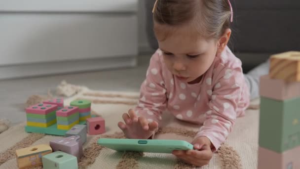 一个蹒跚学步的女孩在手机智能手机上玩电子游戏 — 图库视频影像