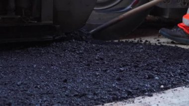Bilinmeyen inşaat işçilerinin ayakları yere asfalt serpiştirilmiş.