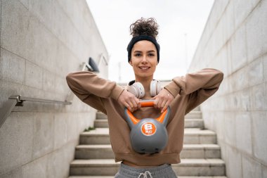 Kafkasyalı genç bir bayan sporcu gün içinde dışarıda Rus çanı Girya Kettlebell ağırlık egzersizi ile antrenman yapıyor.