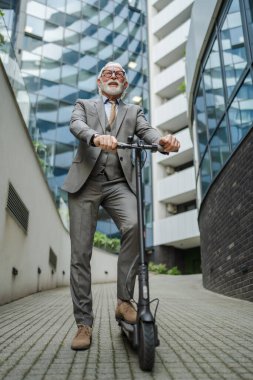 Son sınıf beyaz erkek. Elektrikli scooterın üzerinde duruyor. Şehrin e-scooter çevre dostu ulaşım aracında sürüyor.
