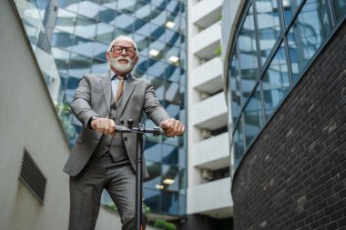Son sınıf beyaz erkek. Elektrikli scooterın üzerinde duruyor. Şehrin e-scooter çevre dostu ulaşım aracında sürüyor.
