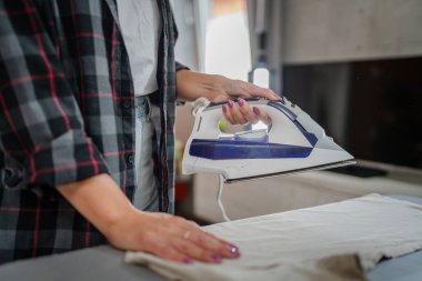 Beyaz, yetişkin bir kadın ev işi ev işi ev işleri ev işleri konsepti için elektrikli ütü kullanıyor.