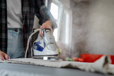 Beyaz, yetişkin bir kadın ev işi ev işi ev işleri ev işleri konsepti için elektrikli ütü kullanıyor.