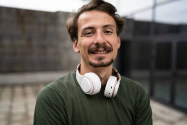 Genç, yetişkin, beyaz erkek, bıyıklı, modern insan portresi. Kulaklık takıyor. Kameraya bakıyor.