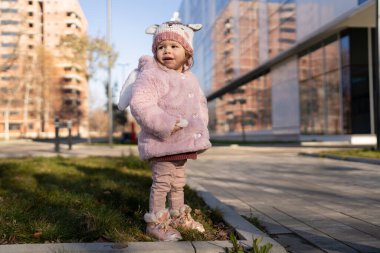 Small caucasian girl toddler in the city outdoor in winter day