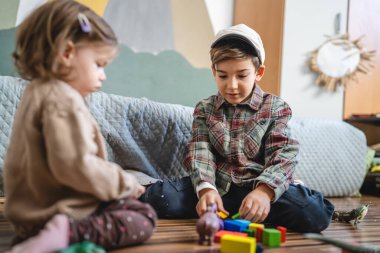 Small caucasian boy and girl siblings brother and sister children play at home sit on the floor at home childhood development growing up concept copy space domestic life