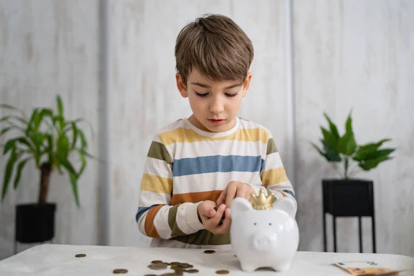 portrait of caucasian boy six years old saving money with piggy bank